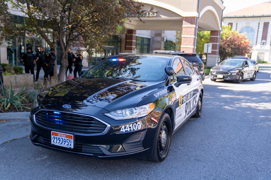 a police car on the road with officers standing nearby