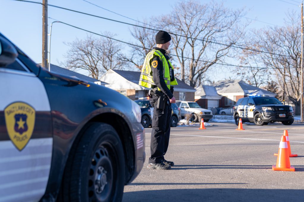 Photo of a police officer and a cop car.