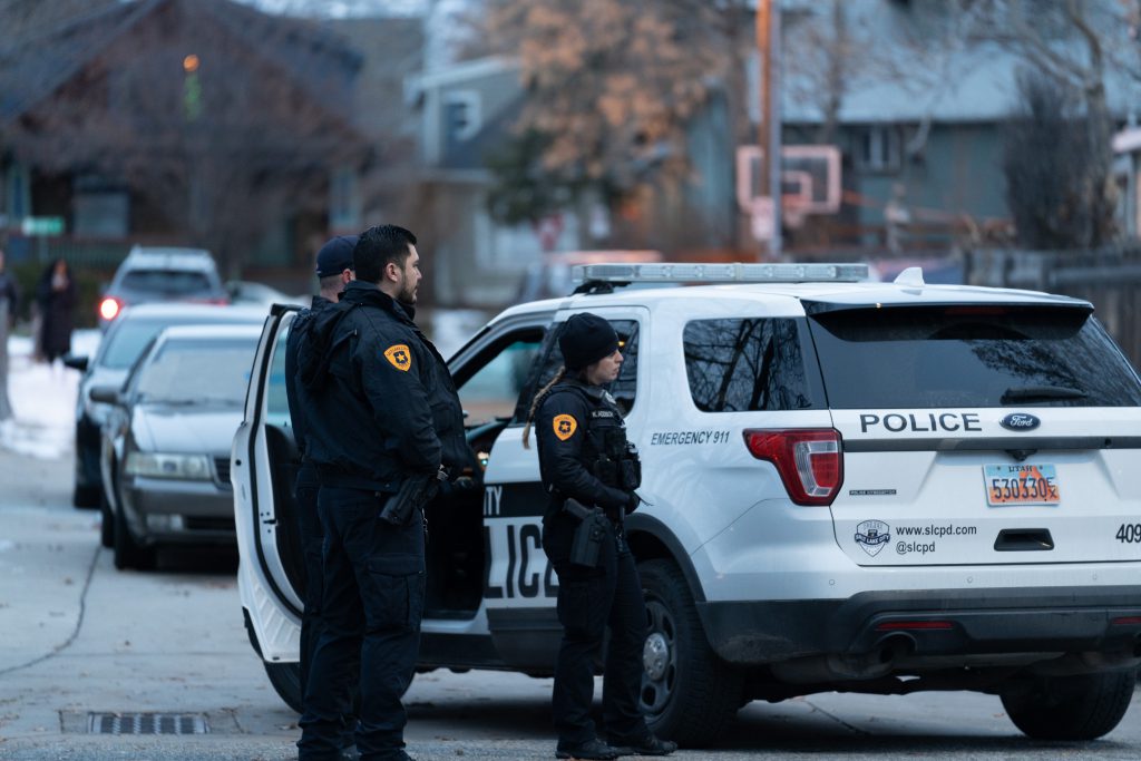 Photo of police officers standing outside of a police car.