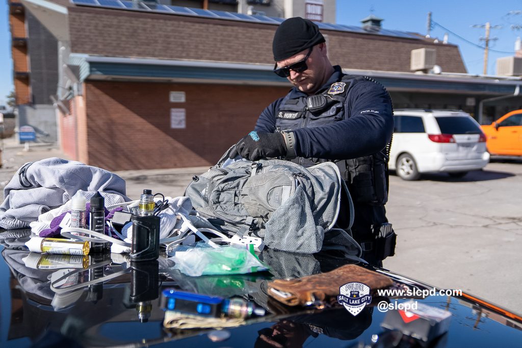 A police officer searching property on the hood of a car