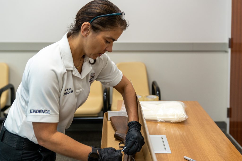 An evidence specialist packaging a firearm turned in by a community member.