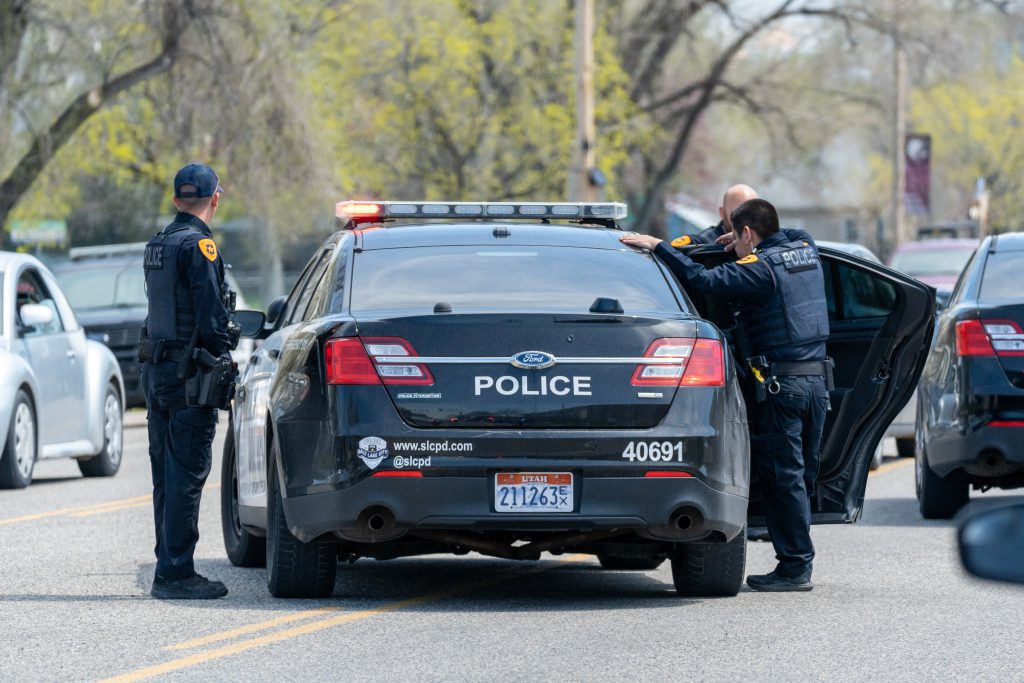 A police car with officers standing nearby