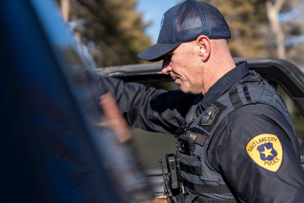 Photo: A Salt Lake City police officer talks to a man accused of illegally possessing a gun and drugs in Liberty Park (SLCPD photo; December 26, 2023).